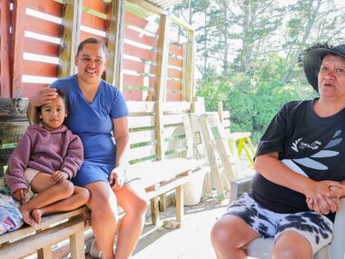 family of three sits on outside their newly repaired home.
